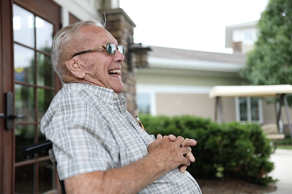 Resident from Oostburg Campus smiling while sitting in his wheelchair outside of the facility